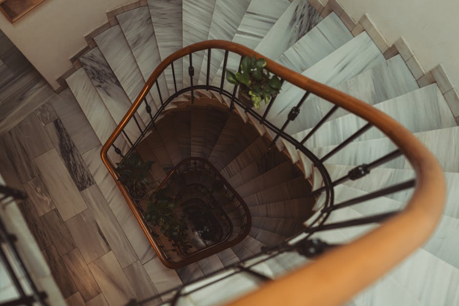 A set of wide, concrete outdoor stairs leading up to an entrance inside a building, with metal handrails on both sides. The stairs appear weathered with visible dirt and wear marks, and are positioned